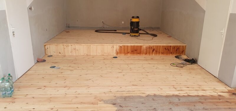 Szlifowanie starych szarych desek w świetlicy wiejskiej